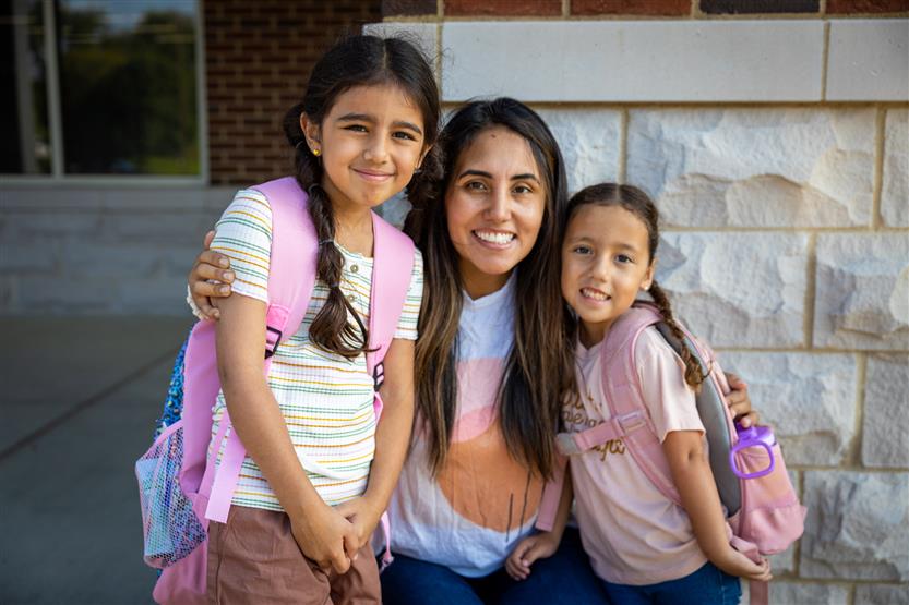 A woman and her two daughters smile